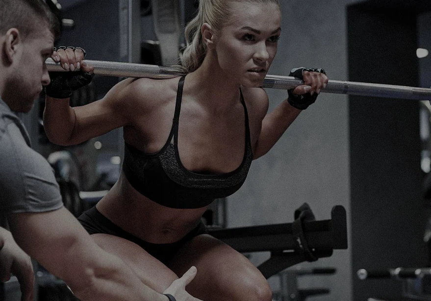 Personal trainer ohjaa kyykkytekniikkaa kuntosalilla