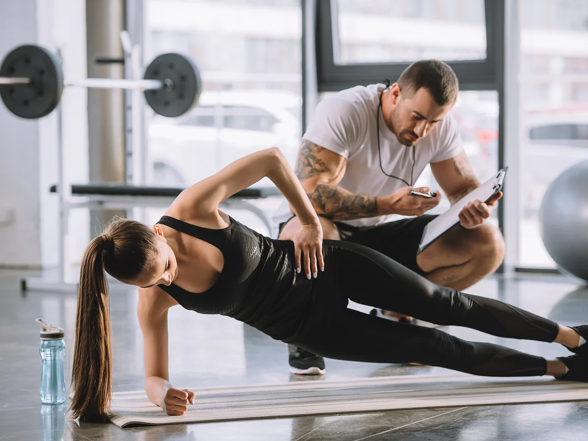 Personal trainer ohjaa asiakkaan liikettä salilla
